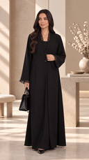 Woman wearing The Kamila Ruffle Trim Abaya with Single-Button Front in an elegant neutral interior