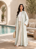 Woman wearing the Rabiha sage green palm print abaya by the pool
