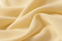 Close-up of soft yellow Nida fabric with a smooth matte finish and fluid drape, highlighting its lightweight texture.