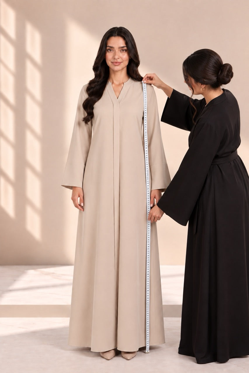 A helper measuring length from shoulder to hem over an abaya